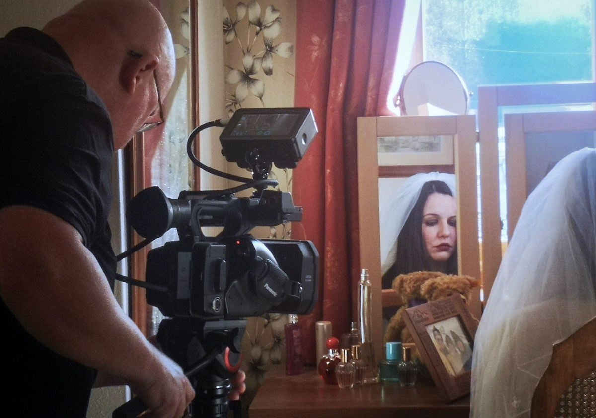 Video production: photograph of camera operator filming a sad faced bride who is reflected in a mirror.