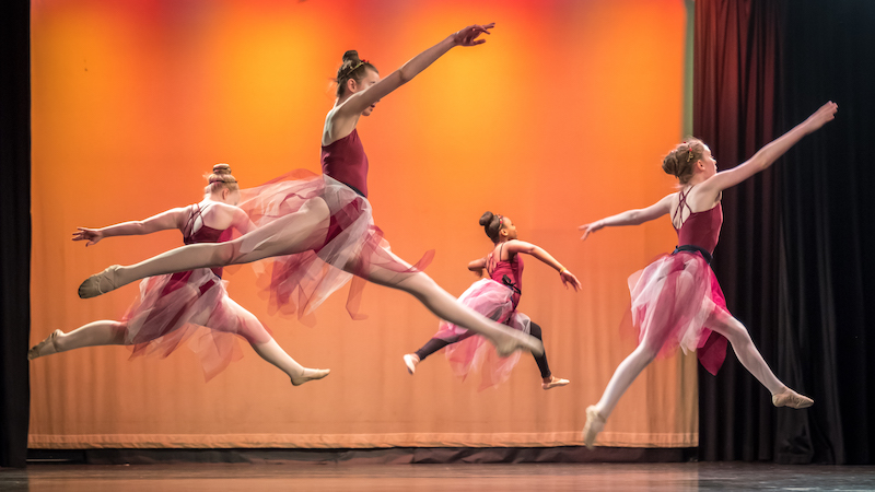 4 teenage ballet dancers performing in a school dance show. 